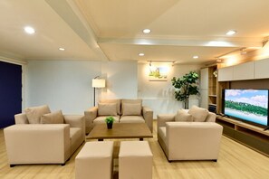 Un salon moderne avec des canapés de couleur beige, une table basse, un téléviseur et une plante.