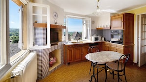 Una cucina con mobili in legno, un tavolo in marmo e vista attraverso una finestra aperta.