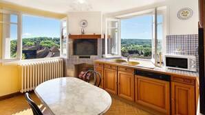 Cucina con vista, pensili in legno, tavolo in marmo e forno a microonde integrato.