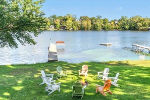 A lakeside setting with a dock, chairs, and a fire pit. - Lake Access Home on Cross Lake: Walk to Dtwn! (Pine City)