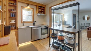 Une cuisine compacte dotée d’appareils électroménagers intégrés, d’étagères en bois et d’un coin repas offrant une vue agréable.
