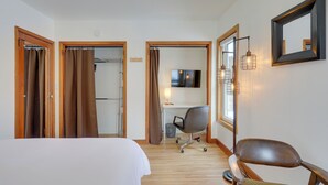 Une chambre d’hôtel équipée d’un lit, d’un bureau, d’une chaise, d’une télévision et d’un miroir.