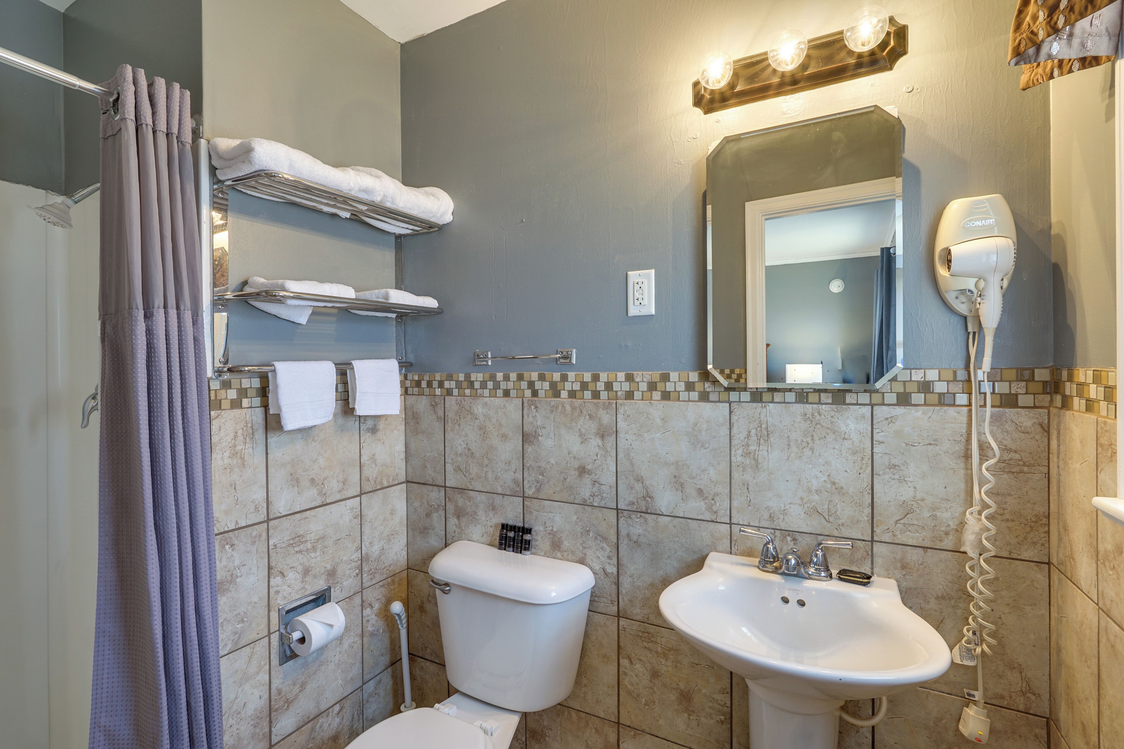 A bathroom with a toilet, sink, towel rack, and hairdryer.
