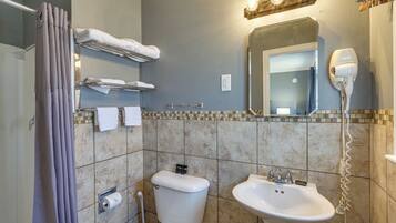 A bathroom with a toilet, sink, towel rack, and hairdryer.