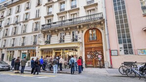 Un bâtiment doté d’une grande entrée en arc de cercle, de nombreuses fenêtres et de balcons.