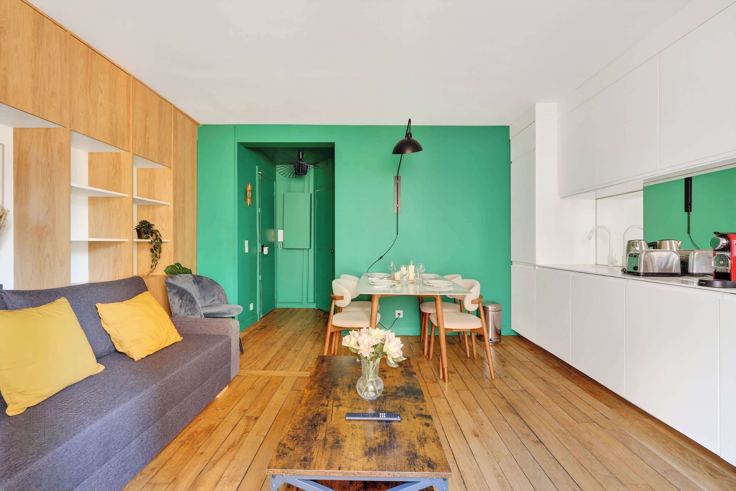 A living room with a sofa, coffee table, and dining area with chairs and a table.