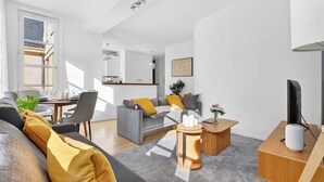 Una sala de estar moderna con un sofá gris, mesitas de madera y un televisor de pantalla plana.
