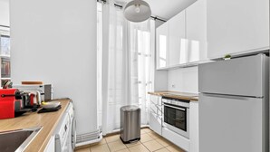 Una cocina moderna con armarios blancos, un cubo de basura de acero inoxidable, un horno empotrado y una encimera de madera.