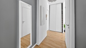 Un pasillo con puertas blancas, suelo de madera y una lámpara en el techo.