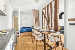 Eine moderne Küche mit Essbereich, Holzboden und einem großen Fenster mit Vorhängen.