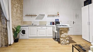 A compact kitchen with a washing machine, a microwave, and a sink. - Quartier Palais Royal - Studio Apartment NetFlix (Paris)