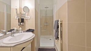 A bathroom with a sink, mirror, shower, and towel rack. - Quartier Palais Royal - Studio Apartment NetFlix (Paris)