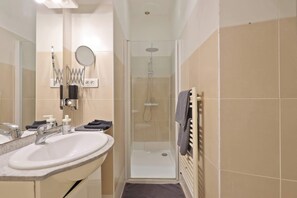 A bathroom with a sink, mirror, shower, and towel rack. - Quartier Palais Royal - Studio Apartment NetFlix (Paris)