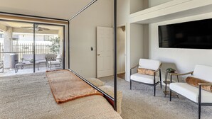 A modern living room with a large TV, comfortable seating, a glass door leading to an outdoor area, and a ceiling fan. - Desert Escape w/ Spool Pool! 4 Mi to Lake Havasu (Lake Havasu City)