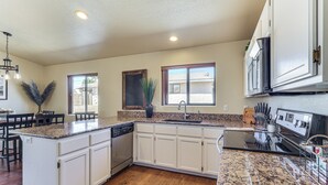 A kitchen with white cabinets, granite countertops, a dishwasher, and a stove. - Desert Escape w/ Spool Pool! 4 Mi to Lake Havasu (Lake Havasu City)
