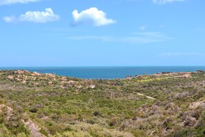 A coastal landscape with scattered buildings, dense vegetation, and a clear view of the sea. - Casa Urania Apartment with Shared Pool, Private Terrace, and Wi-Fi (Liscia di Vacca)