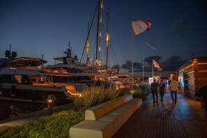 A waterfront promenade with boats docked, a flag, and a walkway. - Casa Urania Apartment with Shared Pool, Private Terrace, and Wi-Fi (Liscia di Vacca)