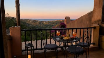 A balcony with a table set for two, overlooking a scenic landscape.