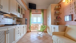A kitchen with cabinets, a green chair, and a sofa.