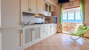 A kitchen with cabinets, a stove, and a dining area with a chair.