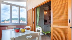 A dining area with a table, chairs, and a view of the landscape through a window.