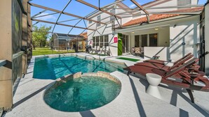 A swimming pool with a hot tub, lounge chairs, and a covered patio area. - 4524 Stella Street (Kissimmee)