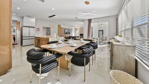 A modern dining area with a wooden table, black upholstered chairs, and a view of the city through large windows. - 4524 Stella Street (Kissimmee)