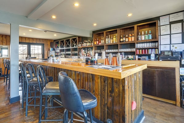 A bar area with wooden shelves, bar stools, and a counter.