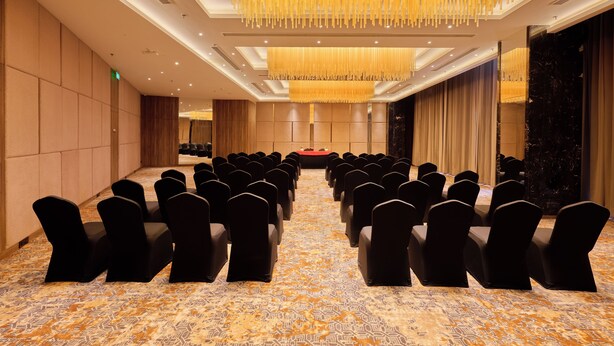 A conference room with rows of chairs, a patterned carpet, and a modern chandelier.