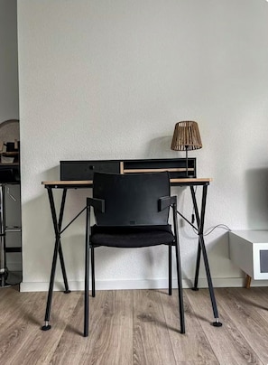 Un bureau moderne avec une chaise noire, une lampe et un mur blanc.