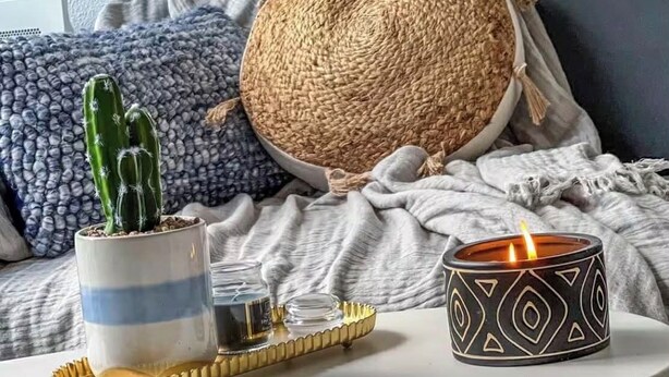 A cozy living room with a round woven pouf, a striped potted plant, and a lit candle on a white coffee table. - Studio Rangueil Close to hospitals and universities Free parking (Toulouse)