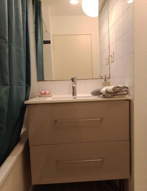 Ein Badezimmer mit Waschbecken, Spiegel und zwei Schubladen.