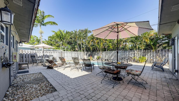 A patio area with outdoor furniture, a pool, and a white fence. - Steps to Beach! Pompano Beach Apt w/ Shared Pool (Pompano Beach)