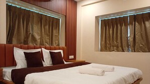 A neatly made bed with white linens, a brown headboard, and a wooden frame. - The Executive Suites (Barasat)