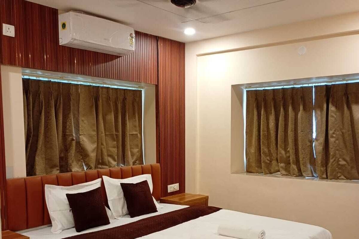 A modern hotel room with a wooden bed, a ceiling fan, and large windows with curtains.