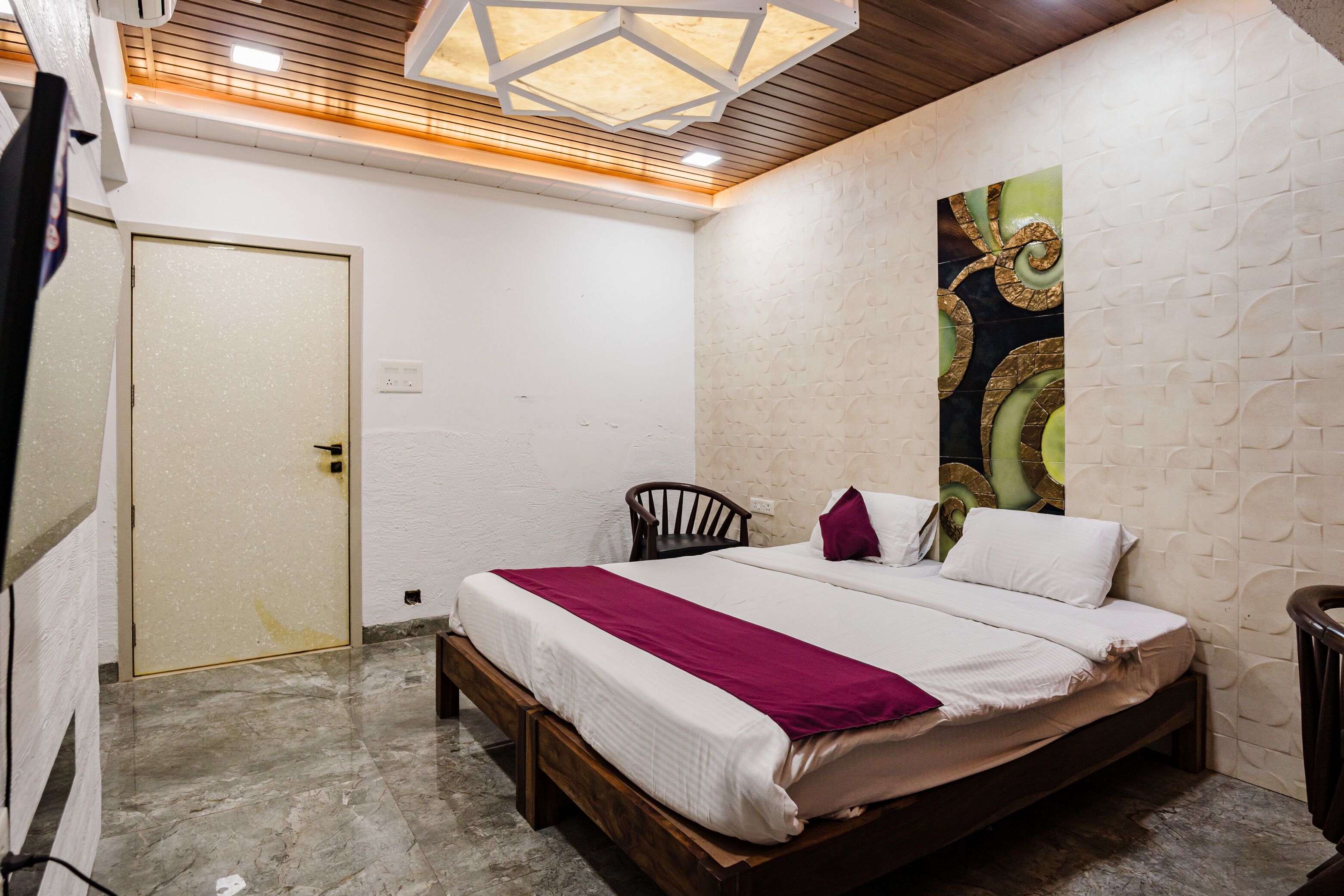 Une chambre à coucher comprenant un lit, une chaise, une porte et un mur orné d’un motif texturé.