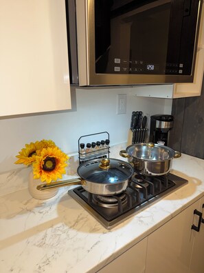 A kitchen with a stove, pots, a microwave, and a vase with sunflowers. - Cozy Loft for Solo Stay Workspace at West Hills and private internet modem (Los Angeles)