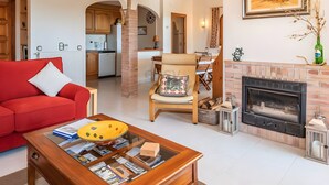 A living room with a red sofa, a wooden coffee table, a fireplace, and an open kitchen in the background. - Casa Baringo, pool and sea view (Calonge)