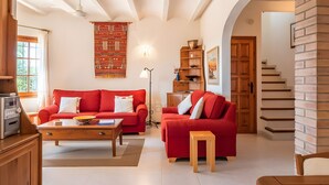 A living room with a red sofa, a wooden coffee table, a lamp, and a staircase leading to another level. - Casa Baringo, pool and sea view (Calonge)