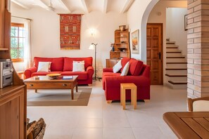 A living room with a red sofa, a wooden coffee table, a lamp, and a staircase leading to another level. - Casa Baringo, pool and sea view (Calonge)