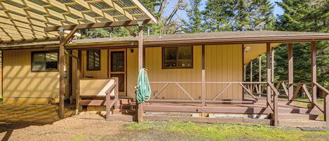 A wooden cabin with a covered porch, a bench, and a hanging towel.