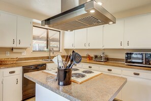 A modern kitchen with white cabinets, a stainless steel range hood, a built-in oven, and a microwave. - Creative Escape! Eagle's Nest Hideaway (Cottage Grove)