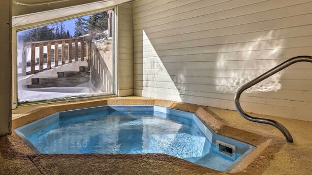 Ein Whirlpool mit Blick auf eine Holzterrasse und eine verschneite Landschaft.