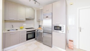A modern kitchen with a built-in oven, a refrigerator, and a microwave. - Solaga - Maestranza (Málaga)