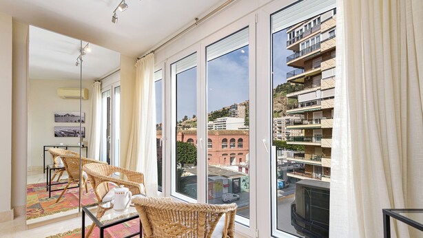 A balcony with wicker chairs, a glass table, and a colorful rug. - Solaga - Maestranza (Málaga)