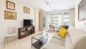 A living room with a sofa, a television, a bookshelf, and a dining area with a table and chairs. - Solaga - Maestranza (Málaga)