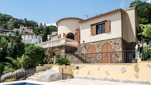 Een villa in mediterrane stijl met een zwembad, stenen muren en een balkon met uitzicht op het zwembad.