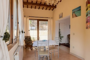 A dining area with a table and chairs, a view through a window, and a door leading to another room. - House with Beautiful Views in a Quiet Area (Calonge)