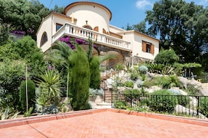 A Mediterranean-style villa with a stone staircase, lush garden, and a paved patio area. - House with Beautiful Views in a Quiet Area (Calonge)