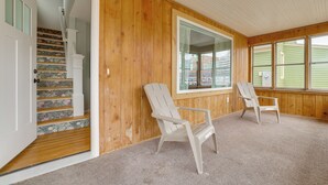 A room with wooden walls, a carpeted floor, a white chair, a window, and a staircase with floral-patterned steps. - Walk to Dtwn: Rochester Home, Private Deck + Yard! (Rochester)